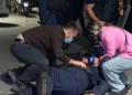 Momenti kur protestuesit ndihmojnë policin e shtrirë për tokë