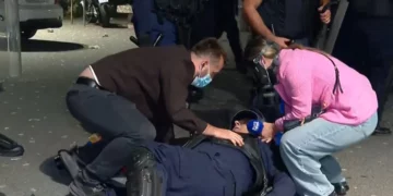 Momenti kur protestuesit ndihmojnë policin e shtrirë për tokë